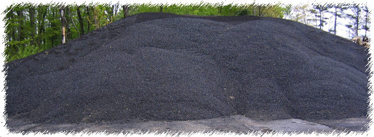 A pile of black dirt in the middle of a field.