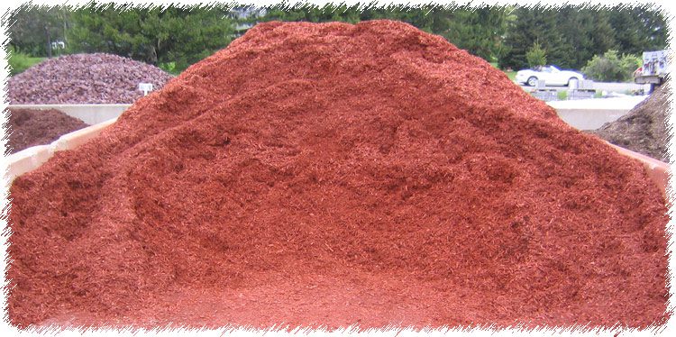 A pile of red dirt on top of the ground.